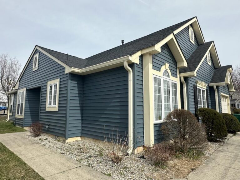 Cream gutters and downspouts along the eaves of a slate-blue clapboard home